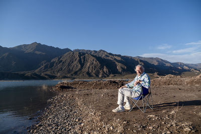 Man sitting in a camping chair while relaxing outdoors in nature.
