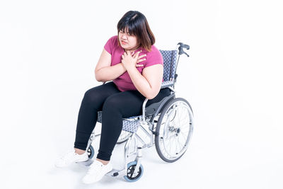 Full length of woman sitting on chair against white background