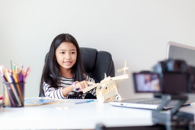 Portrait of young woman using phone while sitting on table