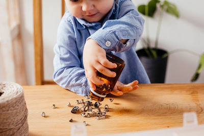 Midsection of boy holding buttons in jar