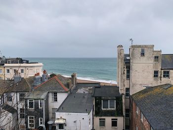 Houses by sea against sky