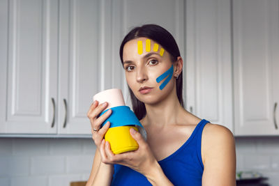 Woman holds three skeins of kinesio tape in her hand yellow and blue