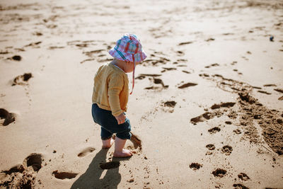 Full length of baby girl standing at sandy beach on sunny day