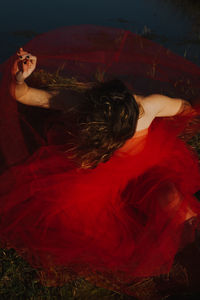 High angle view of young woman wearing red dress while sitting on land