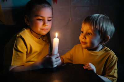 Little children holding burning candles in darkness. high quality photo