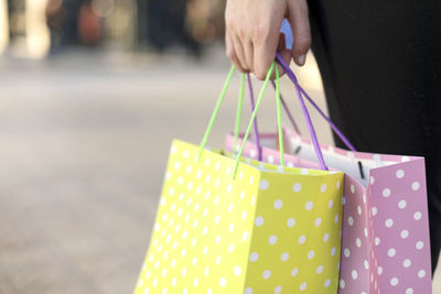 Midsection of woman holding shopping bags in city