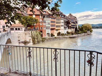 Buildings by river against sky in city