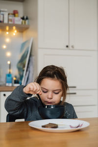 Portrait of cute girl looking away while sitting at home