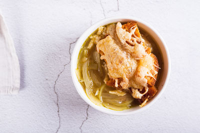 Close up of homemade onion soup with croutons and cheese in a bowl on the table top view