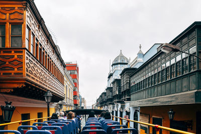 People sitting in open-air bus amidst buildings in city