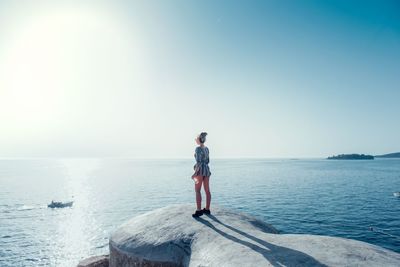 Woman standing on coast against clear sky