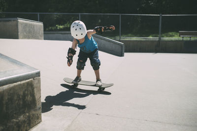 Full length of boy skateboarding at skateboard park during summer