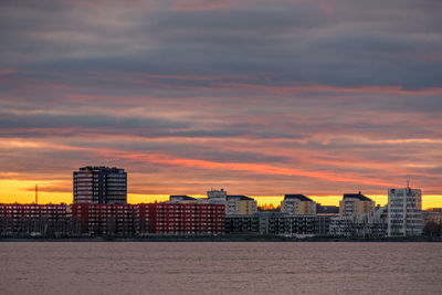 Buildings by sea against romantic sky at sunset