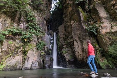 Man standing by waterfall in forest