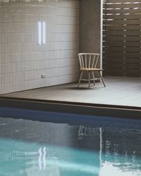 Empty chair by swimming pool