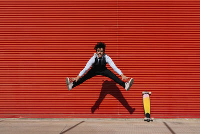 Full length of a young man against red wall