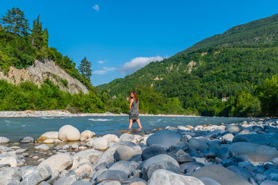 Man standing on rocks by mountain against sky