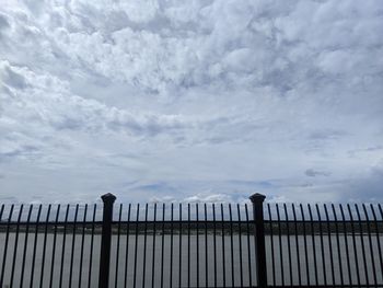 Fence by railing against sky