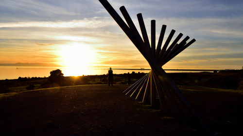 Silhouette person on field against sky during sunset