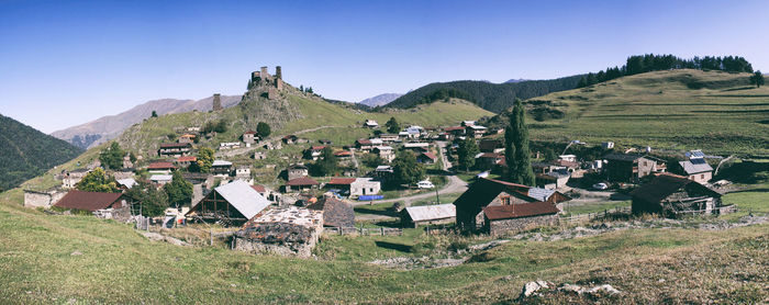 Houses on field by mountains against sky