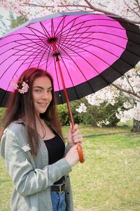 Beautiful young woman with umbrella standing in rain