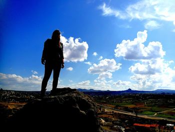 Rear view of man standing on landscape against sky