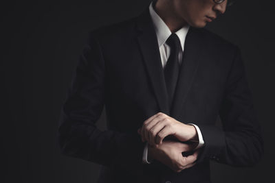 Midsection of man wearing hat against black background