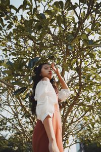 Low angle view of woman standing against tree