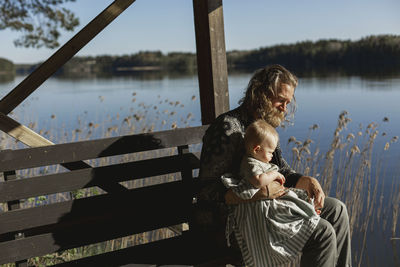 Man sitting at lake with baby son