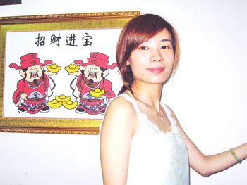 Portrait of smiling young woman standing against wall