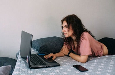 Woman working with laptop and lying on couch. freelancing and work from home.