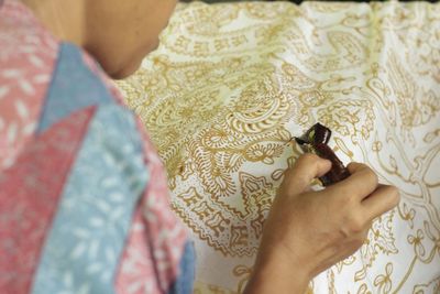 Midsection of young woman making design on fabric