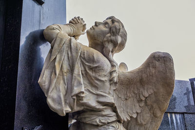 Low angle view of angel statue against sky