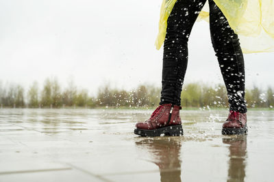 Low section of woman standing in water on footpath