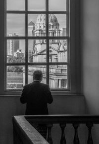 Rear view of woman looking through window