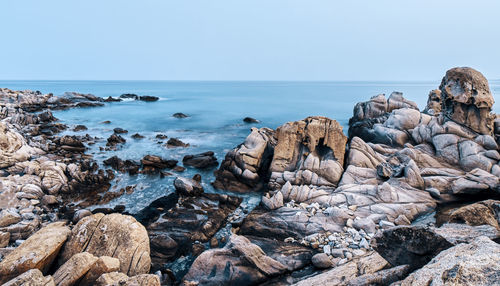 Rocks on beach against clear sky