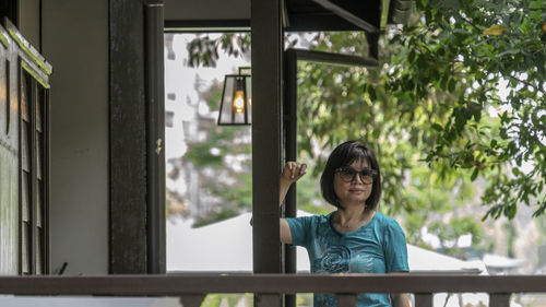 Portrait of a smiling young woman standing against window