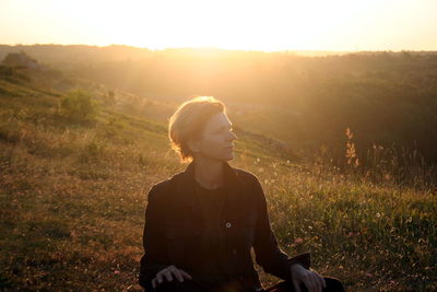 Woman sitting on a hill at sunset