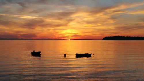 Silhouette boat on sea against orange sky