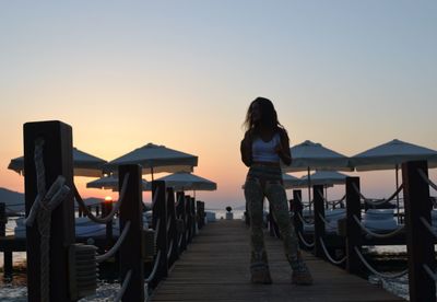 Woman standing on pier in sea against sky