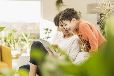 Boy holding mobile phone while sitting at home