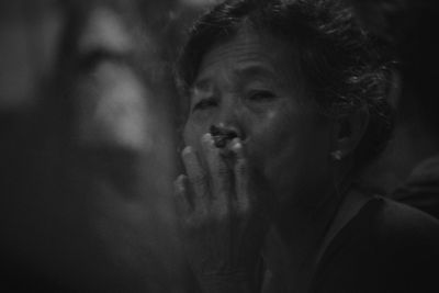 Portrait of mature woman smoking cigarette at night