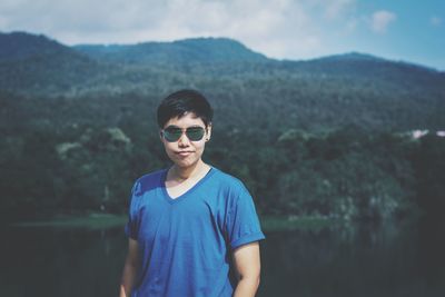 Portrait of mid adult woman wearing sunglasses against lake and mountains