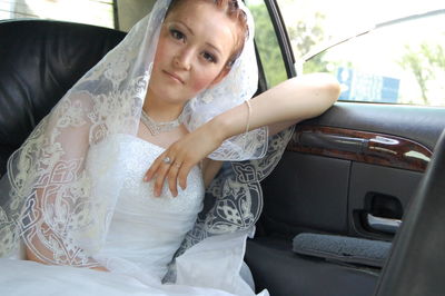 Portrait of beautiful bride traveling in car
