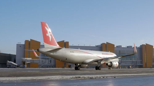 Airplane on airport runway against sky