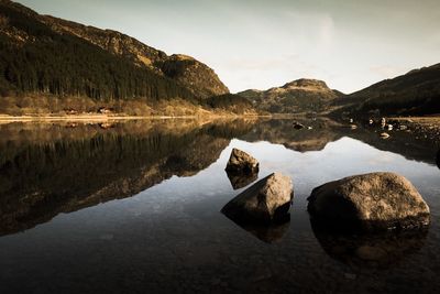 Reflection of rocks in lake against sky