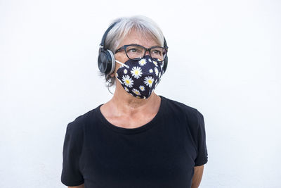 Senior woman wearing mask standing against white background
