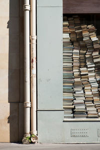 Stack of books on shelf against building