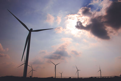 Windmills on field against sky at sunset