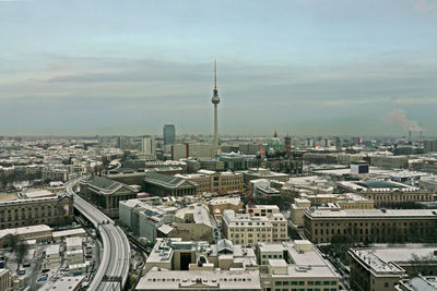 Aerial view of buildings in city against cloudy sky